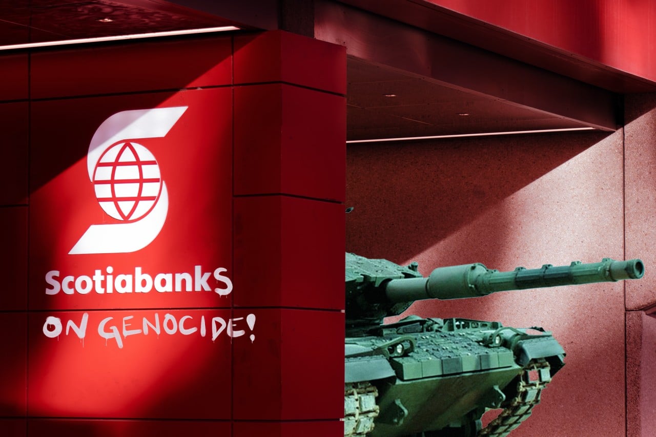 A tank emerges from behind the wall of a Scotiabank, with a sign that has been hit with graffiti to read “Scotiabanks on genocide!”