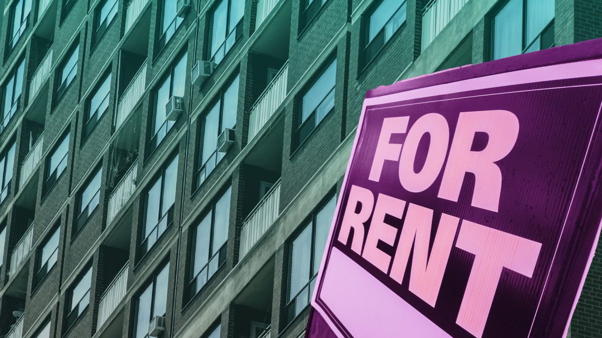An apartment building with a 'for rent' sign in the foreground